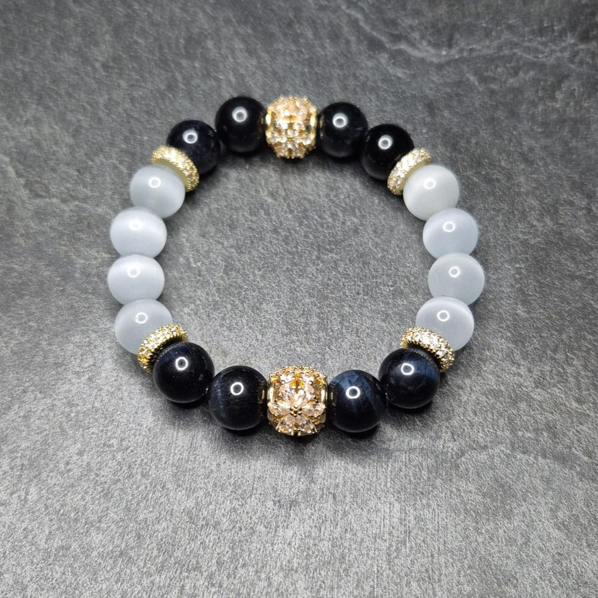 NightVision Armband mit dunkelblauem Falkenauge, weißem Katzenauge und vergoldeten Blütenelementen (925 Silber). Handgemacht in Deutschland. XS–XXXL.