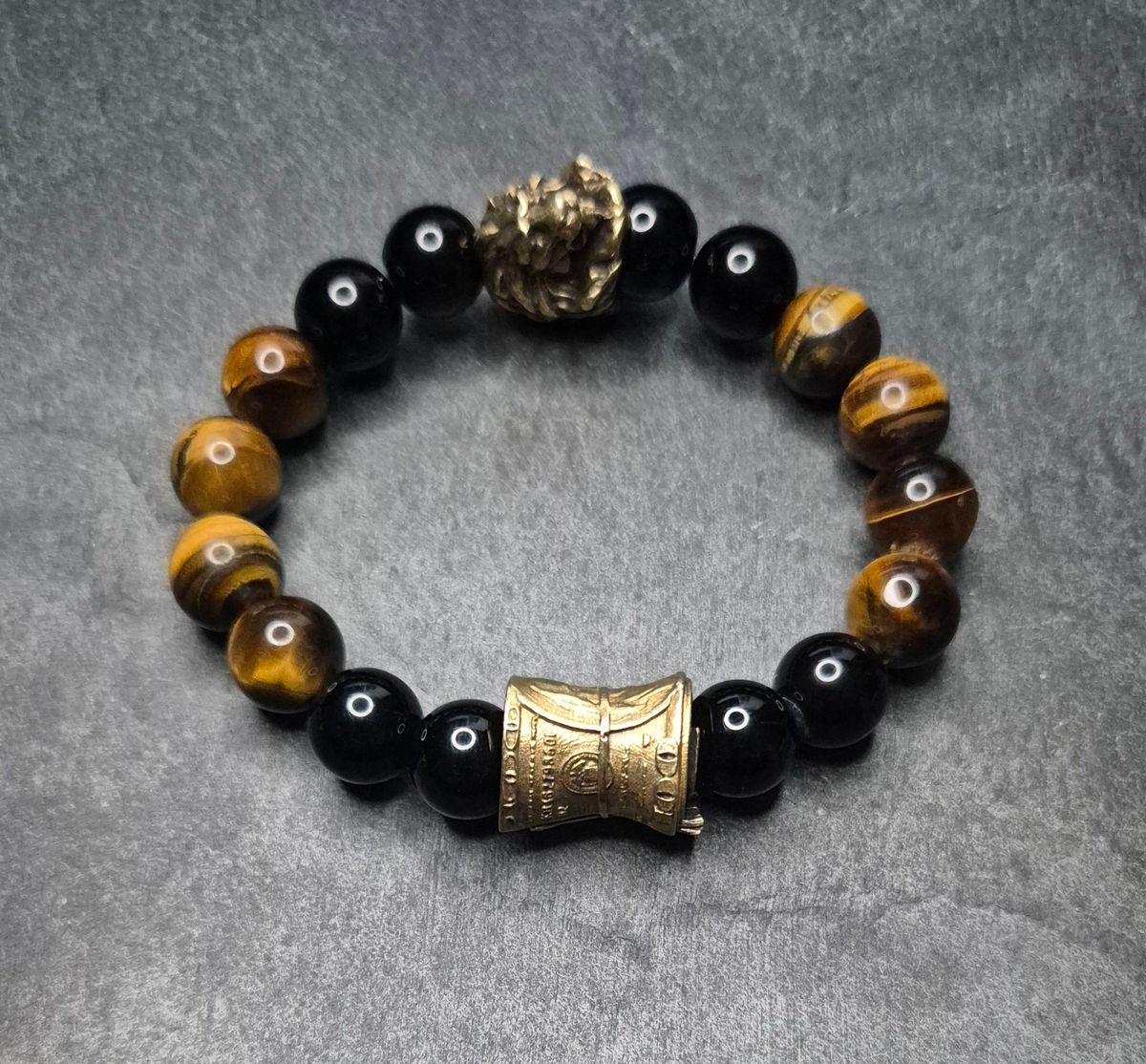 Herrenarmband „CashKing“ in Braun mit Tigerauge, schwarzem Onyx und goldfarbener Geldrolle. 12 mm Perlen. Dominantes Design. Handmade in Germany.