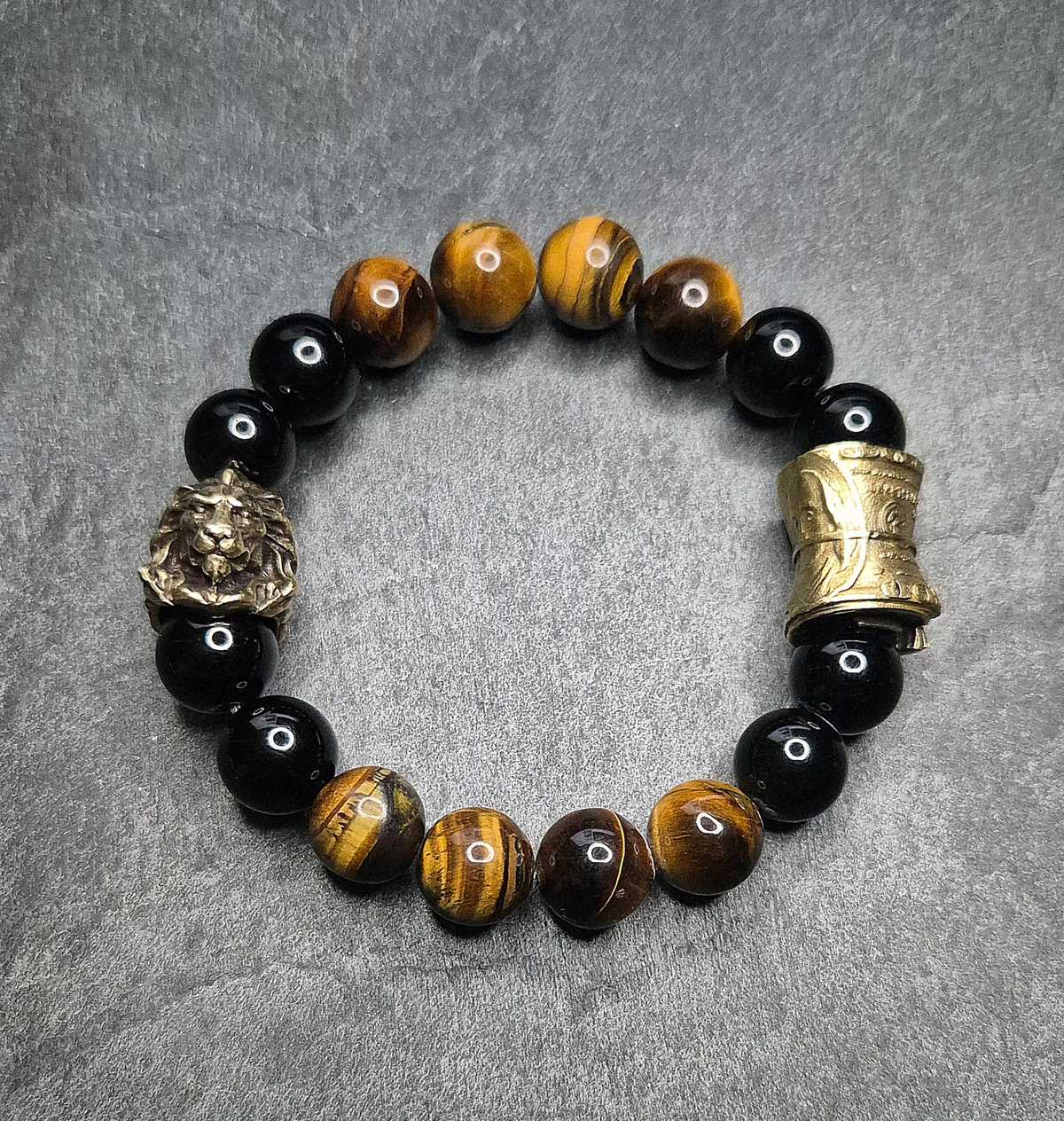 Herrenarmband „CashKing“ in Braun mit Tigerauge, schwarzem Onyx und goldfarbener Geldrolle. 12 mm Perlen. Dominantes Design. Handmade in Germany.